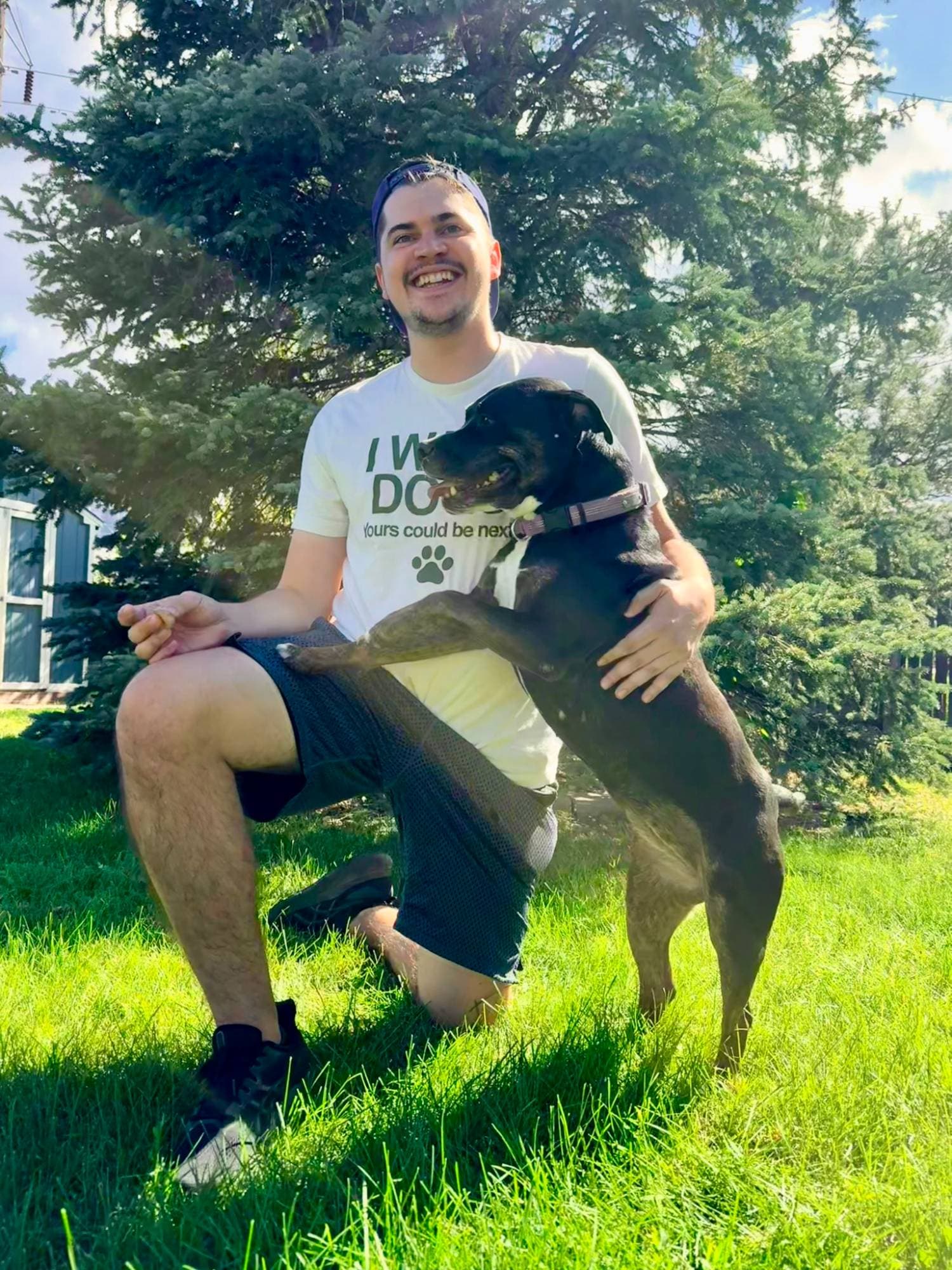 Brandon with a black dog in a sunny yard